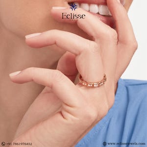 Op de afbeelding: Ros&eacute;gouden ring met afwisselend ronde en rechthoekige heldere stenen. De ring zit om een vinger. De merknaam "Eclisse Jewels" is zichtbaar in het midden van de afbeelding.