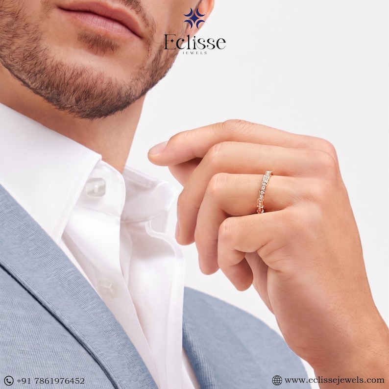 Op de afbeelding: Ros&eacute;gouden ring met kleine, heldere stenen rond de band. De ring zit om de vinger van een persoon, met een wit overhemd en een lichtblauwe blazer op de achtergrond. Het Eclisse Jewels-logo is zichtbaar.
