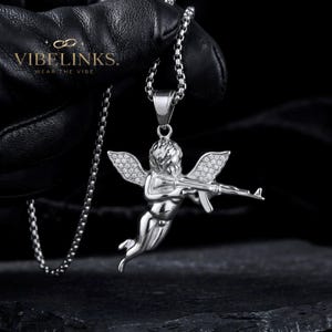 Detailed view of a gold tone angel pendant necklace with pavé CZ crystal wings in stainless steel, showing the sculpted Cupid face, body, and sparkling wing detail, a popular hip hop and festival jewelry accessory with 60cm chain.