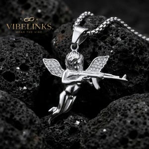 Gold tone and silver tone angel pendant necklaces displayed together on a dark textured background, both with CZ crystal wings and stainless steel box chains, a standout birthday or Christmas gift for fashion-forward men and women.