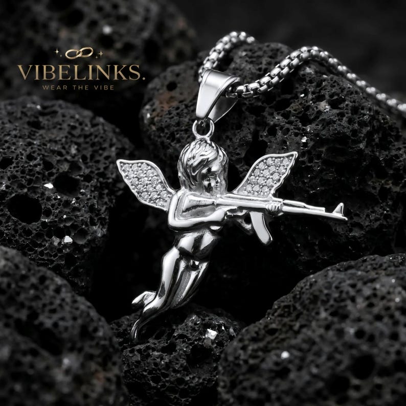 Gold tone and silver tone angel pendant necklaces displayed together on a dark textured background, both with CZ crystal wings and stainless steel box chains, a standout birthday or Christmas gift for fashion-forward men and women.