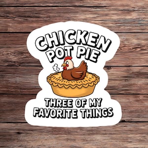 May include: A sticker featuring a cartoon chicken sitting on a pot pie. The text "CHICKEN POT PIE" is above the chicken, and "THREE OF MY FAVORITE THINGS" is below. The chicken is brown with a red comb and yellow beak.