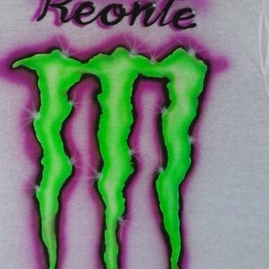 May include: White t-shirt with the name "Keonte" in black script above a neon green and purple graphic. The graphic is a stylized three-claw design with a purple and white gradient background.