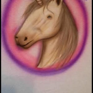 May include: A painted unicorn head with a spiral horn, within a pink and purple circle. The name "Hazel" is written in cursive above the unicorn. The artwork is on a white surface.