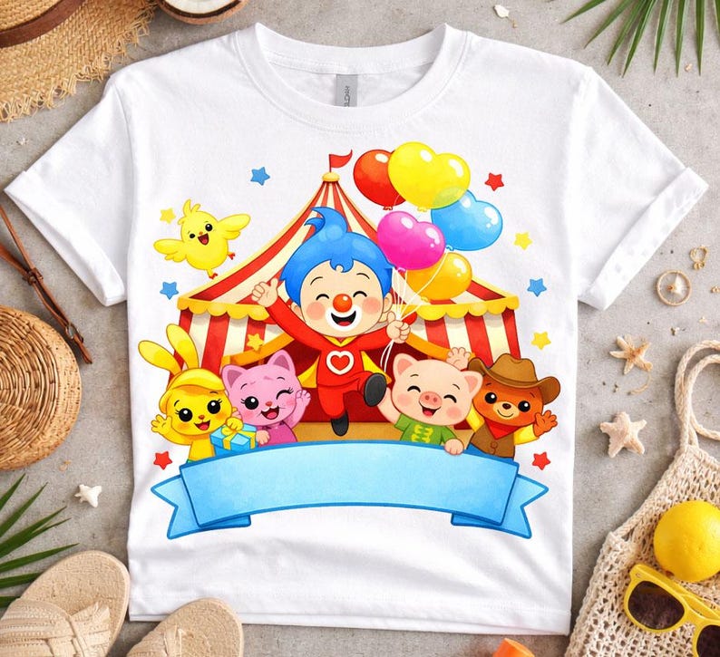 May include: A white short-sleeved t-shirt featuring a colorful graphic of a circus tent, a central clown character, and various animal friends including a yellow chick, a pink cat, a pig, and a bear, all holding heart-shaped balloons.