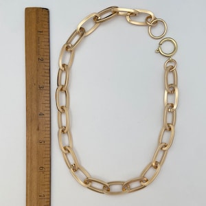 May include: A gold chain necklace with a large oval link design. The chain has a lobster claw clasp.