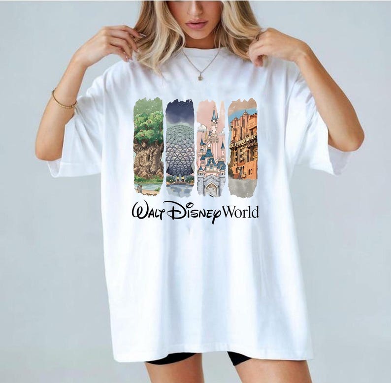 May include: White t-shirt with colourful illustrations of Walt Disney World landmarks. The shirt features images of a tree, Spaceship Earth, a castle, and a building, with the words "Walt Disney World" printed below the images.