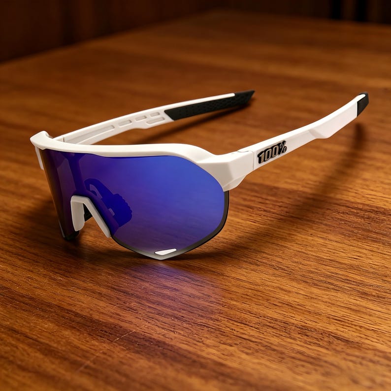 May include: White sports sunglasses with blue mirrored lenses. The sunglasses have a white frame with black accents on the arms and nose bridge. The brand name "100%" is printed on the right arm.