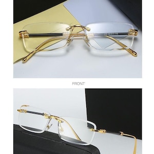 May include: Rimless eyeglasses with gold-colored frames and black temples. The lenses are clear and rectangular. The text "GOLD BLACK/TRANSPARENT" is at the top of the image. The text "FRONT" is in the middle of the image. The text "45&deg;DISPLAY" is at the bottom of the image.