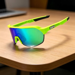 May include: Neon green sports sunglasses with a mirrored lens that reflects blue and green hues. The frame has a sleek, modern design with the text "100%" printed on the temple. The sunglasses are designed for outdoor activities.