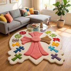 Könnte beinhalten: Ein großer, cremefarbener, unregelmäßig geformter Teppich mit einem markanten, erhabenen, rosa und braunen Kreuzdesign in der Mitte. Der Teppich ist mit verschiedenen kleineren, bunten kreuzförmigen Motiven in Rot, Grün, Blau, Gelb und Violett verziert.