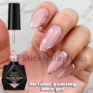 Pode incluir: Um frasco preto de verniz de gel Four Lily UV/LED soak off com uma capacidade de 10 ml. O frasco inclui um pincel aplicador e um rótulo com o texto Gel Nail Polish Liner Nail Gel A0088-3 FL890. As unhas apresentam um design de gel metálico.