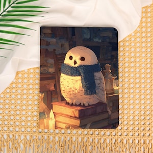 May include: A rectangular print featuring a white owl with a blue knitted scarf perched on a stack of books. The scene is set in a dimly lit room with shelves, glass bottles, and a lit candle, creating a warm, golden glow around the owl.