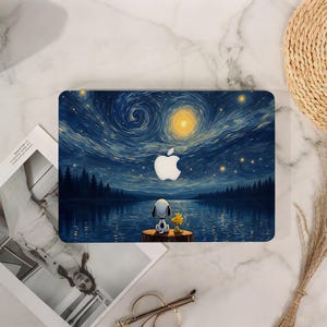 May include: A rectangular laptop skin featuring a dark blue starry night sky with a bright yellow moon, a silhouette of a forest, and a calm lake. A white dog and a small yellow bird sit on a wooden stump. A white Apple logo is centred in the sky.