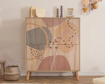 May include: A light wood cabinet with four doors featuring abstract shapes in muted tones of gray, terracotta, and tan. The design includes black dotted lines and small circular wooden knobs. The cabinet stands on four tapered light wood legs.