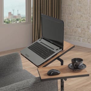 May include: A laptop on a wooden side table with a black metal frame. A black computer mouse and a black coffee cup and saucer are on the lower shelf. The laptop is open, displaying a blank screen.