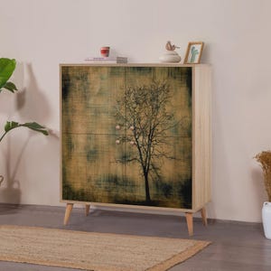 Könnte beinhalten: Ein helles Holzschrank mit einem Baumdesign auf der Vorderseite. Der Baum ist vor einem strukturierten, braunen und grünen Hintergrund silhouettiert. Der Schrank hat vier Türen und vier Holzbeine.