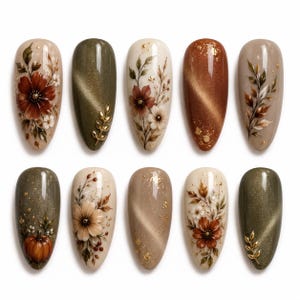 May include: Ten almond-shaped press-on nails featuring autumn-themed designs. The set includes cream, olive green, and copper tones with hand-painted floral motifs, gold leaf accents, a small pumpkin illustration, and metallic cat-eye finishes.
