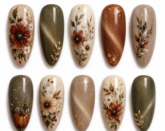 May include: Ten almond-shaped press-on nails featuring autumn-themed designs. The set includes cream, olive green, and copper tones with hand-painted floral motifs, gold leaf accents, a small pumpkin illustration, and metallic cat-eye finishes.