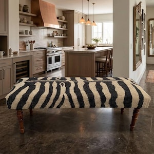 Könnte beinhalten: Rechteckige Bank mit Zebra-Streifenmuster in Schwarz und Beige. Die Bank hat dunkle Holzbeine und steht in einer modernen Küche mit neutralen Tönen und Edelstahlgeräten.