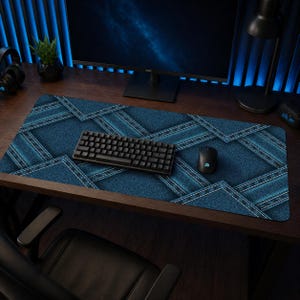 Peut inclure: Tapis de bureau bleu avec un motif denim et des coutures blanches, un clavier noir et une souris noire. Le tapis est posé sur un bureau en bois, avec un écran d'ordinateur, une lampe de bureau et une petite plante en arrière-plan. Le tapis est rectangulaire.