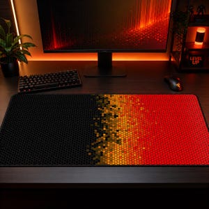 May include: A rectangular gaming mouse pad with a honeycomb pattern. The pad transitions from black to a gradient of orange and red. A keyboard and mouse are visible on the desk, along with a computer monitor.