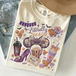 May include: A cream-colored t-shirt featuring a purple and orange graphic print with the text "Magical Literally Just A Girl" and "Let the MAGIC Begin!". The design includes illustrations of mouse-ear headbands, a high-heeled shoe, and cups.