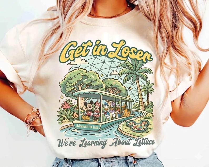 May include: Cream-colored t-shirt with a retro-style graphic featuring Mickey and Minnie Mouse, Donald Duck, and Goofy on a boat ride. The text "Get in Loser" and "We're Learning About Lettuce" are also displayed.