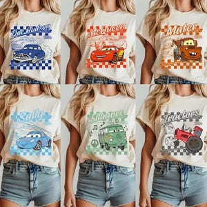 Pode incluir: Seis camisetas bege com personagens do filme "Carros". Cada camisa mostra o nome e a imagem de um personagem diferente, como Doc Hudson, McQueen, Mater, Sally, Fillmore e Tractors, em estilo retr&ocirc;.
