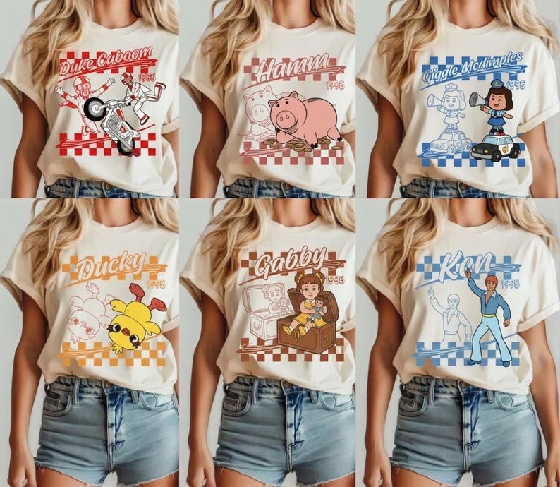 Pode incluir: Seis camisetas creme com gr&aacute;ficos de desenhos animados. Cada camisa apresenta um nome e imagem de personagem diferente, incluindo Duke Caboom, Hamm, Giggle McDimples, Ducky, Gabby e Ken, com um fundo quadriculado e o ano de 1995.