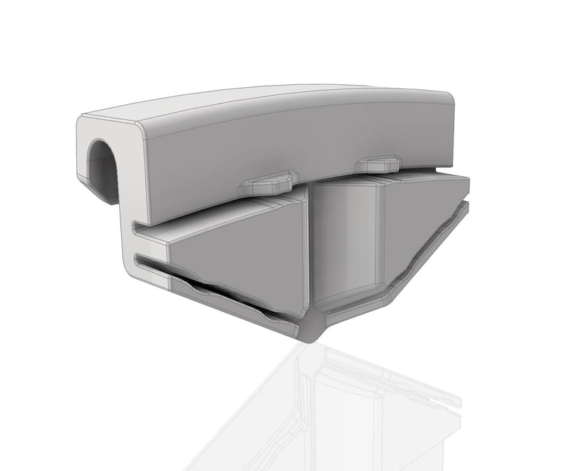 Op de afbeelding: Een lichtgrijs, driedimensionaal object met een gebogen bovenkant en een rechthoekige basis. Het object heeft een uitgehold gedeelte aan &eacute;&eacute;n uiteinde en verschillende uitstekende elementen. Het ontwerp lijkt een onderdeel of deel van een grotere structuur te zijn.