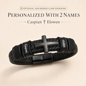 May include: A black braided bracelet featuring a central black cross charm and two cylindrical metal beads engraved with the names Caspian and Elowen. The text above reads OPTIONAL: ADD HIDDEN CLASP ENGRAVING, PERSONALIZED WITH 2 NAMES, Caspian † Elowen.