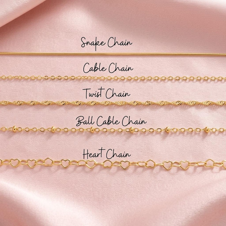 Puede incluir: Una selecci&oacute;n de collares dorados sobre una superficie de sat&eacute;n rosa. Los collares incluyen una cadena de serpiente, una cadena de cable, una cadena trenzada, una cadena de bolas y una cadena de coraz&oacute;n. Cada estilo de cadena est&aacute; etiquetado.