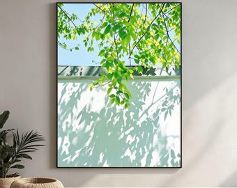 May include: A framed wall art print featuring a bright blue sky above a white wall. Vibrant green leaves hang down from the top, casting intricate, dark shadows across the lower portion of the wall, creating a high-contrast natural scene.