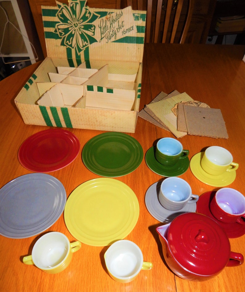 May include: A vintage Little Hostess Party Set in its original box. The set includes a red teapot, four teacups, four saucers, four plates, and a yellow plate. The set is made of plastic and is in good condition.