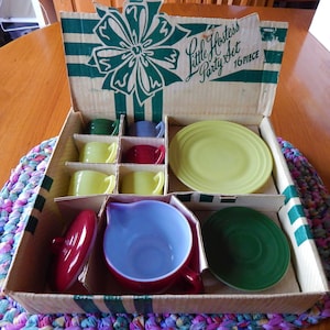 May include: A vintage Little Hostess Party Set in a cardboard box with a green and white striped design. The set includes a teapot, cups, saucers, and a plate. The box is labeled "Little Hostess Party Set 16 PIECE".