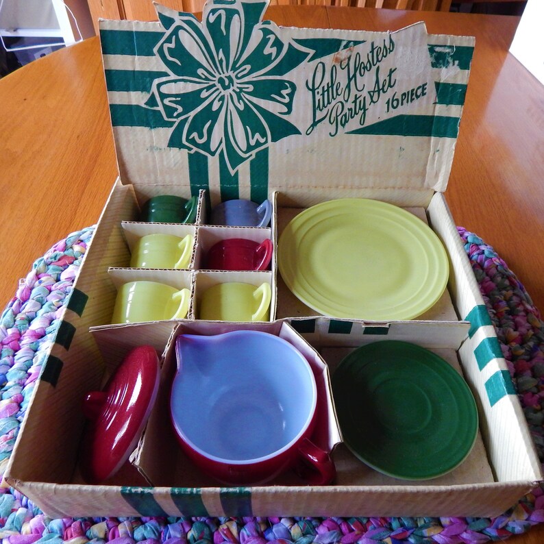 May include: A vintage Little Hostess Party Set in a cardboard box with a green and white striped design. The set includes a teapot, cups, saucers, and a plate. The box is labeled "Little Hostess Party Set 16 PIECE".