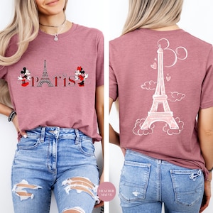 Puede incluir: Camiseta color malva con la Torre Eiffel y la palabra "París" con personajes de Mickey y Minnie Mouse. La parte trasera de la camiseta tiene un dibujo de la Torre Eiffel.