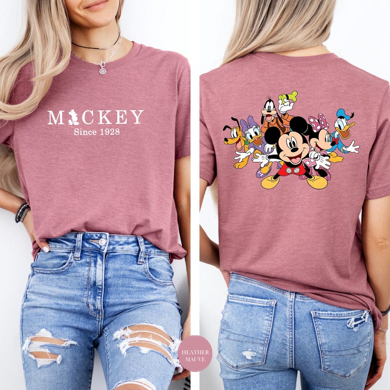 Puede incluir: Camiseta color malva con Mickey Mouse y sus amigos. La parte delantera de la camiseta muestra el texto "Mickey Since 1928". La parte trasera de la camiseta presenta un gr&aacute;fico colorido de Mickey Mouse, Minnie Mouse, Donald Duck, Daisy Duck, Goofy y Pluto.
