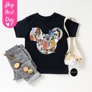 May include: Black t-shirt featuring a Mickey Mouse head design filled with various cartoon dog characters. The shirt is paired with gray pants, a wooden pencil, and small wooden circles. A toy camera and the text "Ship Next Day" are also visible.