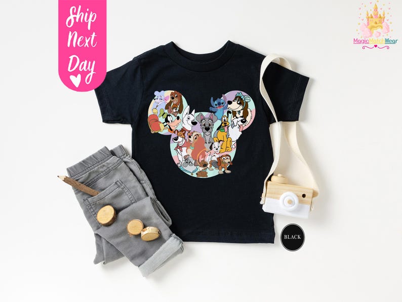 May include: Black t-shirt featuring a Mickey Mouse head design filled with various cartoon dog characters. The shirt is paired with gray pants, a wooden pencil, and small wooden circles. A toy camera and the text "Ship Next Day" are also visible.