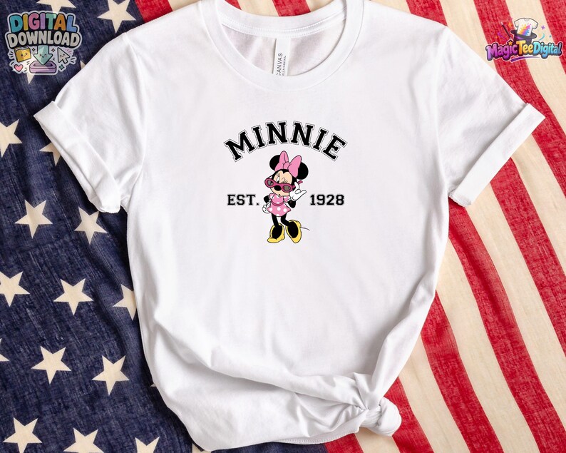 May include: A white short-sleeved t-shirt featuring a graphic of Minnie Mouse wearing pink sunglasses and a polka dot dress. The text above the character reads MINNIE in a black arched font, with EST. 1928 printed in black on either side of the figure.