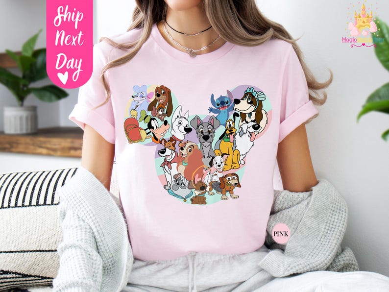 May include: Pink t-shirt featuring a Mickey Mouse-shaped design filled with various cartoon dog characters. The shirt has short sleeves and the text "Ship Next Day" is visible on the left side. The word "Pink" is also visible on the right side.