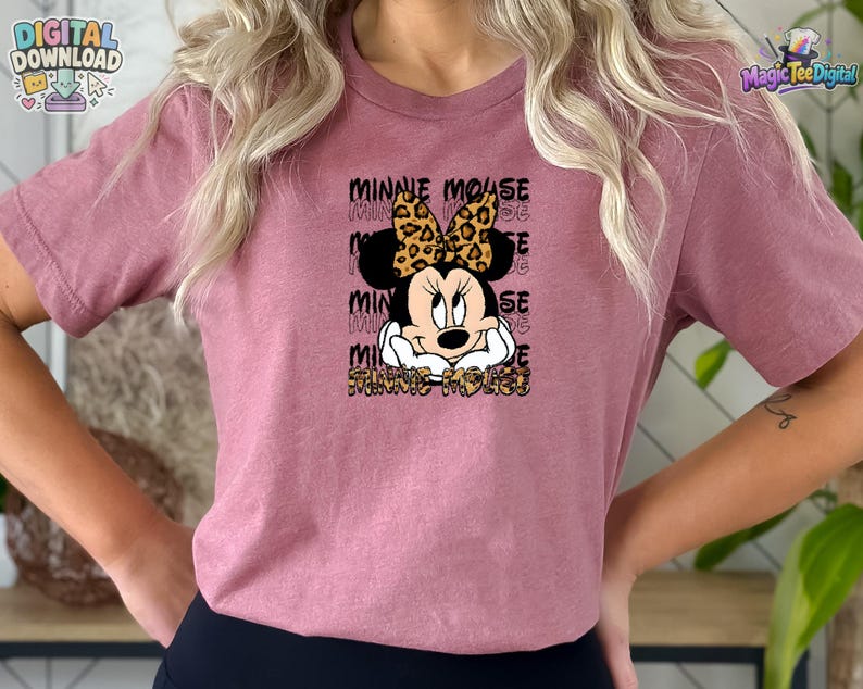 Pode incluir: Uma t-shirt malva de manga curta com um gr&aacute;fico de um rato de desenho animado com um la&ccedil;o de estampado de leopardo. O texto Minnie Mouse &eacute; repetido no fundo e impresso num padr&atilde;o de leopardo na parte inferior do design gr&aacute;fico.