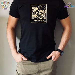 K&ouml;nnte beinhalten: Ein schwarzes T-Shirt mit kurzen &Auml;rmeln und einer cremefarbenen rechteckigen Grafik auf der Brust. Die Grafik zeigt eine Gruppe von Zeichentrickfiguren in einem Polaroid-Rahmen mit Feuerwerk dar&uuml;ber und dem Text DISNEY WORLD 2024 darunter.