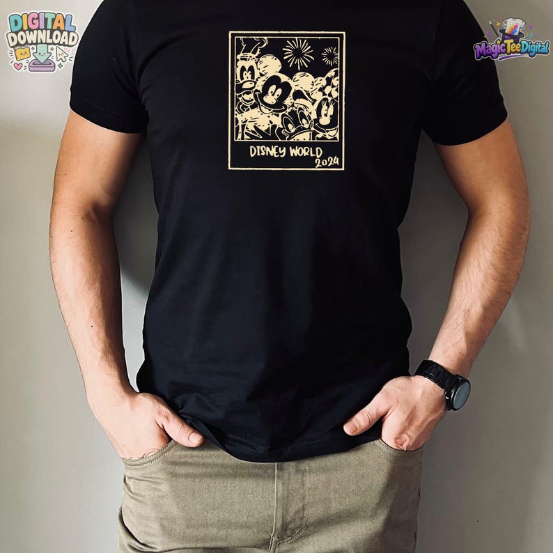 K&ouml;nnte beinhalten: Ein schwarzes T-Shirt mit kurzen &Auml;rmeln und einer cremefarbenen rechteckigen Grafik auf der Brust. Die Grafik zeigt eine Gruppe von Zeichentrickfiguren in einem Polaroid-Rahmen mit Feuerwerk dar&uuml;ber und dem Text DISNEY WORLD 2024 darunter.