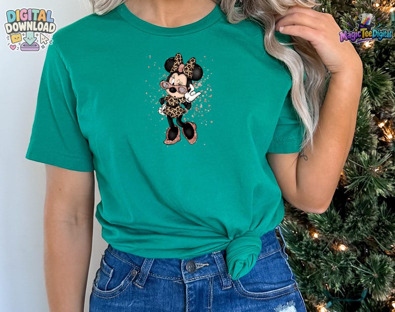 May include: A bright green short-sleeved t-shirt featuring a central graphic of a cartoon mouse character wearing a leopard print outfit, a matching bow, and pink-tinted glasses, surrounded by small copper-coloured glitter-like speckles.