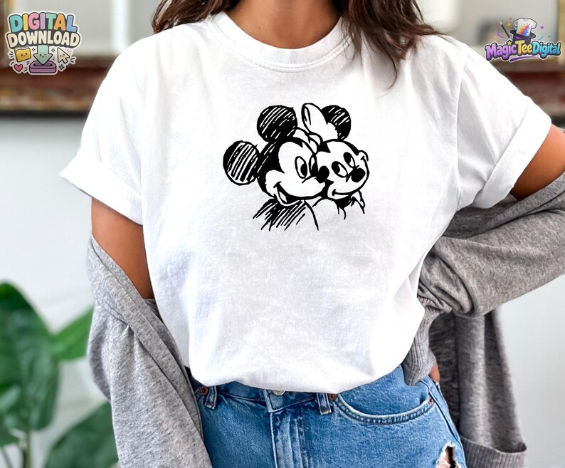 May include: A white short-sleeved t-shirt featuring a black ink-style sketch graphic of two cartoon mice characters positioned side-by-side on the chest. The design uses hatched lines to create the faces and round ears of the characters.