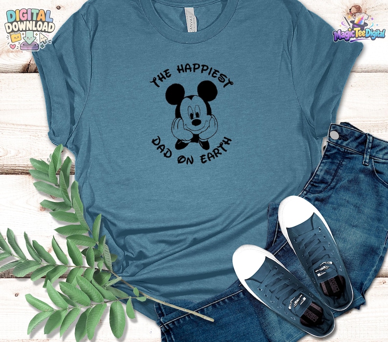Puede incluir: Una camiseta azul pizarra con un gr&aacute;fico negro de un rat&oacute;n de dibujos animados con las manos en la cara, rodeado por el texto THE HAPPIEST DAD ON EARTH. La camiseta se combina con vaqueros azul oscuro y zapatillas de lona azules a juego.