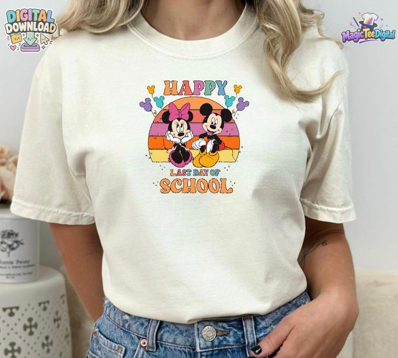 May include: A cream-colored short-sleeve t-shirt featuring a graphic of Mickey and Minnie Mouse. The design includes a sunset background, colorful balloons, and the text "HAPPY LAST DAY OF SCHOOL" in a retro-style font centered on the chest.